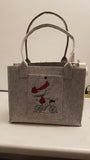 Filztasche aus hellgrauem Filz mit Fach vorne bestickt mit Mädchen auf Fahhrrad und mit Kam Snap Kunststoff-Druckknopf